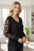 Blusa manga larga con cuello en V y malla con apliques de flores negra